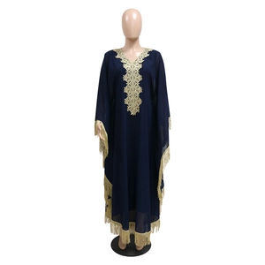 Détails de broderie florale dorée et franges sur une robe caftan bleu foncé chic