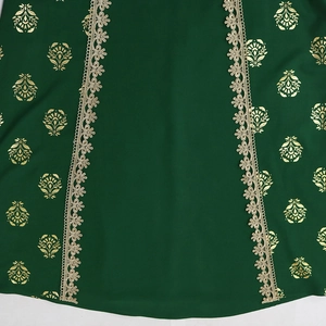 Detail of dark green chiffon fabric featuring gold floral prints and lace trim