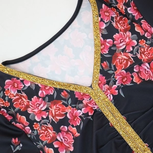 Detailed view of V-neckline with gold sequins and pink rose print on black fabric