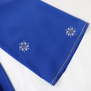 Detail of royal blue kaftan featuring bell sleeves with crystal flowers and gold bead trim