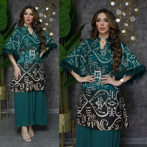 Detail von Kaftan Ethno-Print-Oberteil mit grünen Federbündchen und Faltenhose mit weitem Bein
