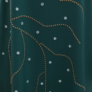 Détail macro de tissu vert foncé avec clous dorés et motifs en strass