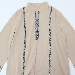 Détail de la robe Jalabiya beige avec ruban tissé décoratif noir et blanc sur l'encolure