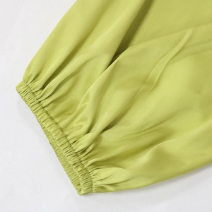 Detail of lime green satin fabric showing elastic pleated cuffs and silky texture