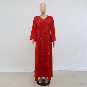 Gros plan détaillé du motif ondulé doré avec strass sur une robe longue rouge
