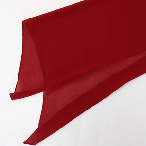 Close-up of dark red chiffon sequin evening dress fabric with neat stitched edges