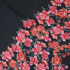 Macro shot of vibrant red rose floral print on black fabric for kaftan dress