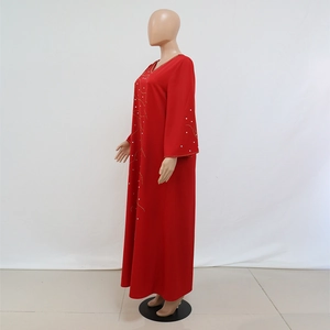 Détail de la robe caftan rouge avec broderies dorées et accents de perles blanches