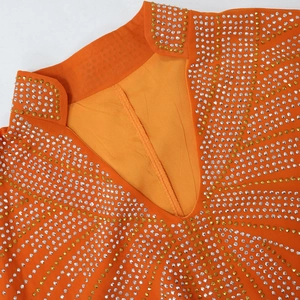 Macro detail of the orange kaftan dress featuring intricate gold and silver rhinestone embroidery