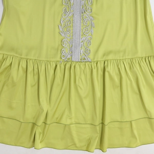 Detail of green satin dress featuring elegant lace trim and layered ruffle hemline