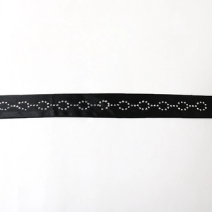 Dettaglio dell'elegante cintura in raso nero con motivo in strass argentati brillanti