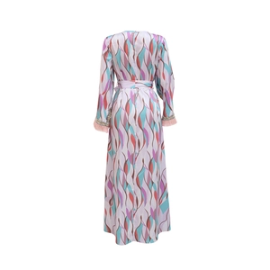Detail of printed kaftan dress with pink feather cuffs and abstract wavy patterns