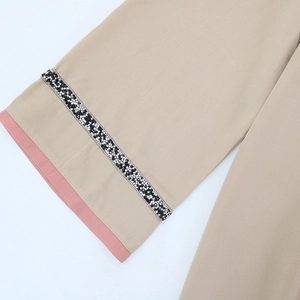 Détail de manche de jalabiya kaki avec ruban de strass et bordure contrastée rose