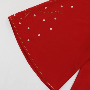 Détail du tissu rouge avec motifs complexes en strass dorés et cristaux clairs