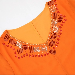 Détail du col en V en mousseline orange orné de strass rouges et blancs étincelants