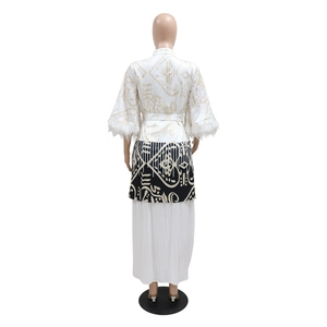 Detailansicht des Kaftan-Kleids mit Ethno-Print, weißen Federn und plissiertem Saum