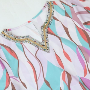 Close-up of V-neckline with intricate multi-color rhinestone beadwork and abstract print
