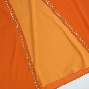 Close-up of sparkling rhinestone trim on bright orange chiffon kaftan dress with belt