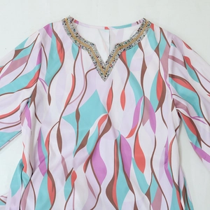 Detail of V-neckline with colorful beads and sequins on an abstract print dress