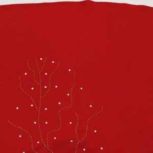 Détail de strass blancs étincelants et clous dorés sur une robe caftan rouge ample