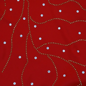 Détail macro du tissu rouge avec strass argentés et motifs de vagues en perles dorées