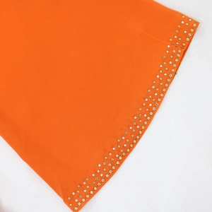 Détail d'une robe en mousseline orange avec trois rangées de paillettes argentées et dorées