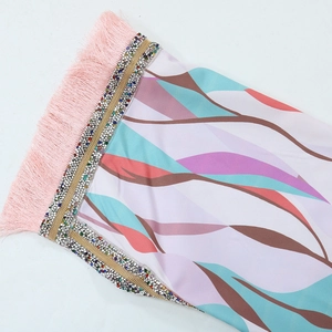 Close-up of printed chiffon caftan with pink fringe tassels and colorful rhinestone trim