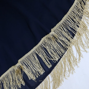 Détails d'un tissu bleu marine avec une élégante bordure de franges dorées