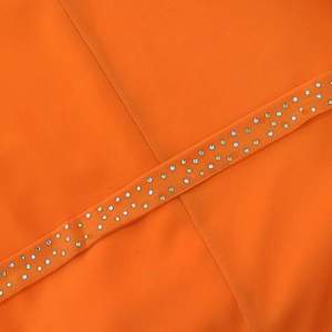 Gros plan de strass colorés étincelants sur le tissu orange d'une robe en mousseline