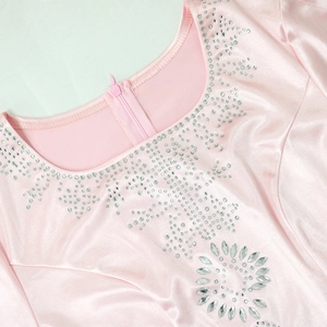Dettaglio dello scollo dell'abito in raso rosa con strass scintillanti e fiore di cristallo