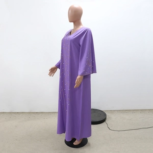 Détail de la robe ample violette avec perles dorées et strass blancs sur les manches évasées