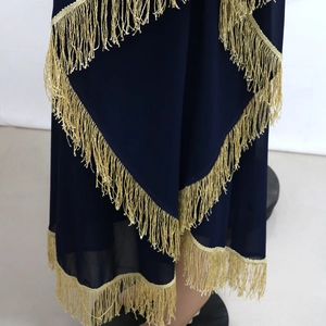Détail d'une robe caftan bleu marine avec ourlet à volants et franges dorées