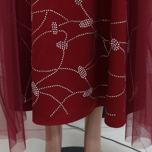 Detailed view of wine red dress featuring silver rhinestone wavy patterns and mesh layer