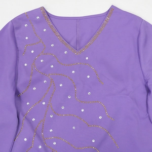Détail du col en V sur robe violette avec strass dorés et motifs de vagues scintillants