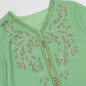 Detail of mint green V-neck dress with red rhinestones and pearl embellishments