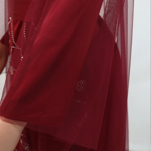 Close-up of semi-transparent burgundy tulle fabric with sparkling silver rhinestone detail