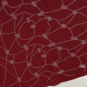 Macro detail of wine red fabric with intricate silver rhinestone geometric patterns