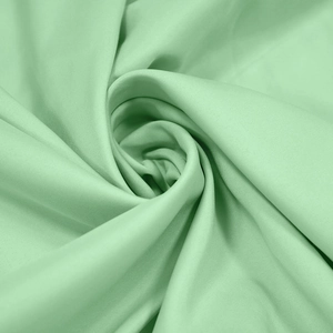 Close-up of mint green kaftan dress fabric with elegant drapes and smooth satin texture