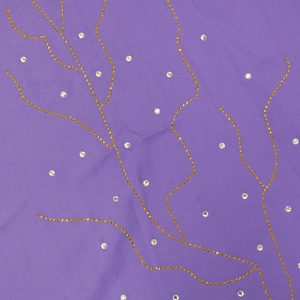 Détail de tissu violet avec des motifs de branches en strass dorés et accents argentés