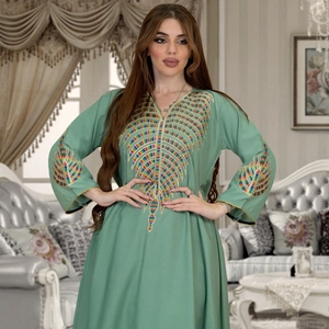 Detailed close-up of colorful leaf embroidery on a light green V-neck maxi dress