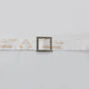 Detail eines weißen Kaftan-Gürtels aus Satin mit Druck und luxuriöser Strass-Schnalle