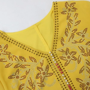Close-up of bright yellow V-neck kaftan dress with rhinestone floral embroidery and pearls