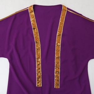 Dettaglio dell'abito tunica viola con finiture in paillettes dorate e ricami eleganti