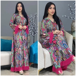 Détail d'une robe maxi bohème aux imprimés colorés et longues franges roses