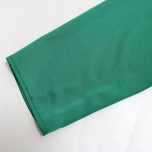Detailed view of emerald green dress sleeve with fine stitching and silk-like texture