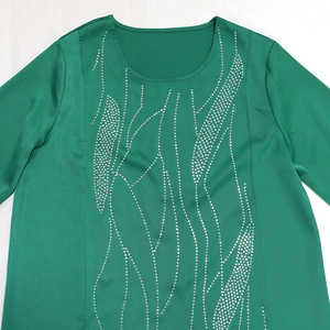Detail of green long-sleeve dress with shiny silver rhinestone wavy pattern on neckline