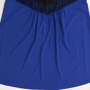 Detail of royal blue chiffon dress featuring black lace trim and draped fabric texture