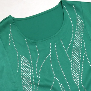 Close-up of sparkling silver rhinestone wave patterns on emerald green dress bodice