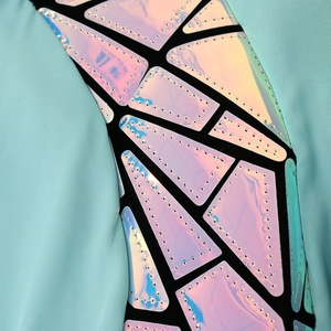 Macro shot of mint green knit fabric with laser-cut iridescent geometric sequins and stitching