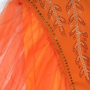 Detail of orange dress showing intricate sequin floral embroidery and layered mesh ruffles